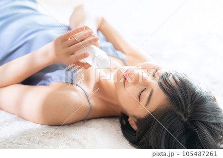 寝転んでスキンケアをする若い女性 105487261