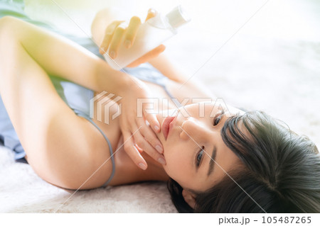寝転んでスキンケアをする若い女性 寝転んでスキンケアをする若い女性 105487265