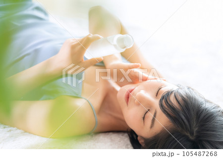 寝転んでスキンケアをする若い女性 寝転んでスキンケアをする若い女性 105487268