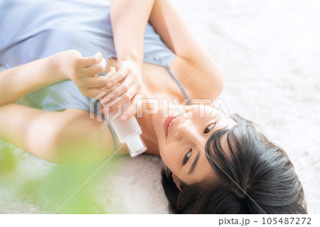 寝転んでスキンケアをする若い女性 寝転んでスキンケアをする若い女性 105487272
