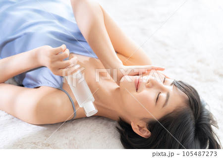 寝転んでスキンケアをする若い女性 105487273