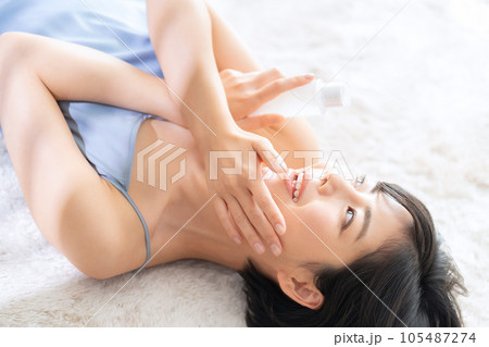 寝転んでスキンケアをする若い女性 105487274