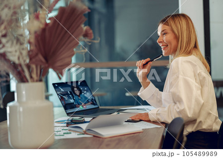 Smiling businesswoman talking with client via videocall while sitting in modern coworking space 105489989