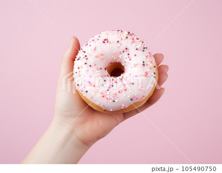 Female hand with pink donut on minimalist background 105490750