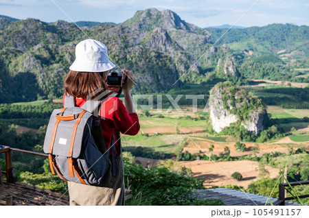 Back view of young tourist woman looking to beautiful scenery view of Pha Chang Noi in Phu Langka Forest Park during green season in Phayao province of Thailand. Back view of young tourist woman looking to beautiful scenery view of Pha Chang Noi in Phu Langka Forest Park during green season in Phayao province of Thailand. 105491157