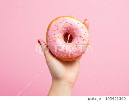 Female hand with pink donut on minimalist background 105491360
