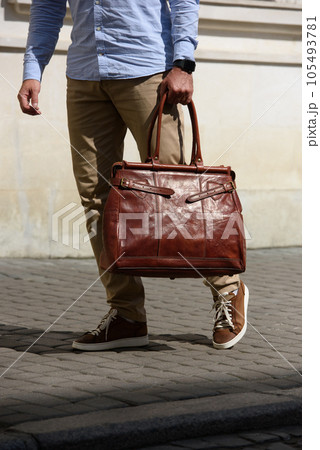 Handsome businessman walking on the street, with luxury brown leather briefcase. Fashionable style. 105493781