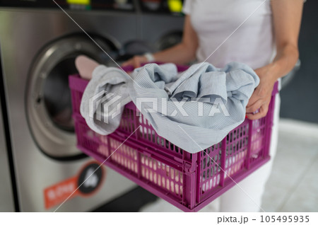 Woman using qualified laundry machine in the public room to wash her cloths. Woman using qualified laundry machine in the public room to wash her cloths. 105495935