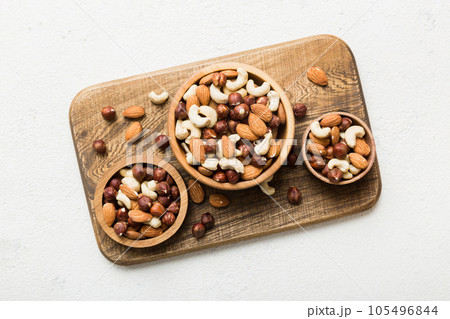 Assortment of nuts in wooden bowl on colored table. Cashew, hazelnuts, walnuts, almonds. Mix of nuts Top view with copy space Assortment of nuts in wooden bowl on colored table. Cashew, hazelnuts, walnuts, almonds. Mix of nuts Top view with copy space 105496844