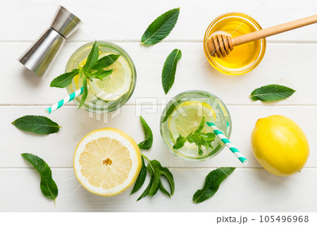 Caipirinha, Mojito cocktail, vodka or soda drink with lime, mint and straw on table background. Refreshing beverage with mint and lime in glass top view flat lay 105496968