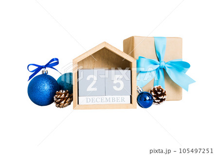 25 december. Christmas composition on colored background with a wooden calendar, with a gift box, toys, bauble copy space 25 december. Christmas composition on colored background with a wooden calendar, with a gift box, toys, bauble copy space 105497251