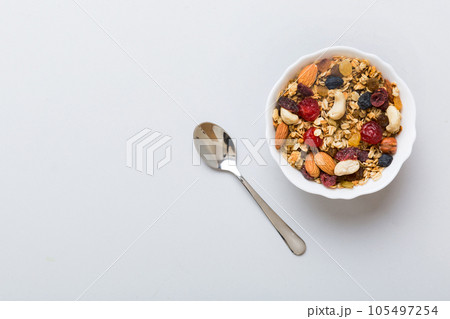 Cooking a wholesome breakfast. Granola with Various dried fruits and nuts in a bowl. The concept of a healthy dessert. Flat lay, top view with copy space Cooking a wholesome breakfast. Granola with Various dried fruits and nuts in a bowl. The concept of a healthy dessert. Flat lay, top view with copy space 105497254