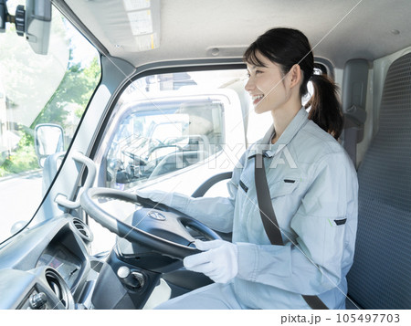 運転席に座る作業着を着た若い女性トラックドライバー 105497703