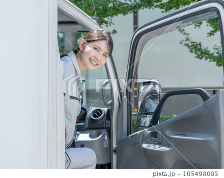 運転席に座って後ろを確認する作業着を着た若い女性トラックドライバー 105498085