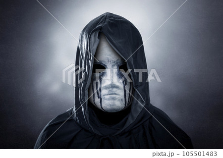 Spooky figure with hooded cape over dark misty background  105501483