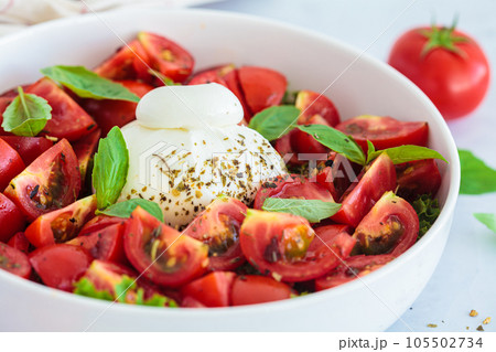 Burrata salad with tomatoes and basil in white plate. 105502734