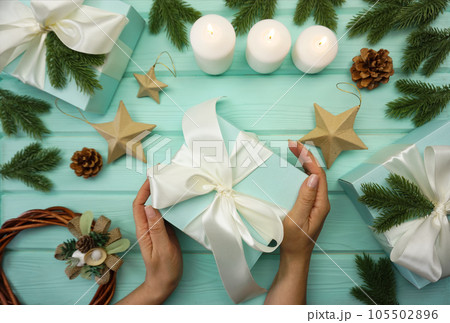 Women's hands are packing a Christmas gift. Women's hands are holding a gift.  105502896
