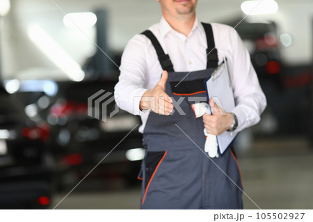 Auto service mechanic greets client with handshake Auto service mechanic greets client with handshake 105502927