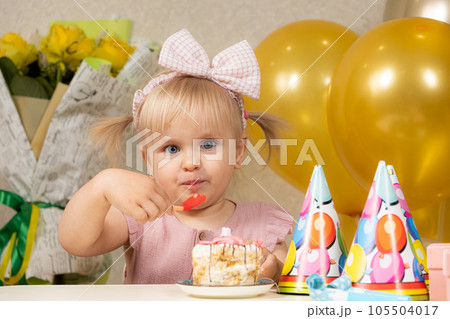 Two-year-old blonde girl eating birthday cake on her birthday. 105504017