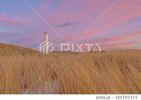 Panorama over the dunes and lighthouse of the Danish coastal resort of Blavand at sunset Panorama over the dunes and lighthouse of the Danish coastal resort of Blavand at sunset 105505315