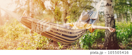 Woman lying in the hammock with hat on her face. 105505416