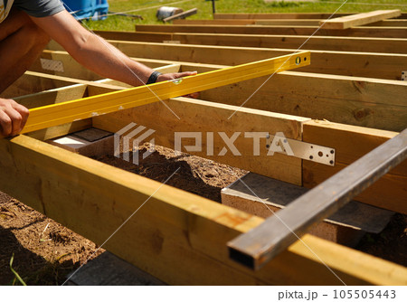 Male construction worker with level tool at construction site. an image of carpenters' hands checking the level of wood on a construction site 105505443