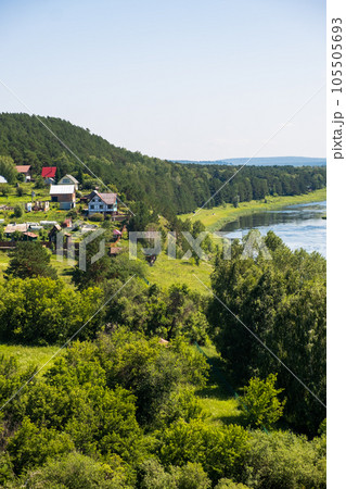 Houses along a beautiful, wide river in the middle of the forest. Calm and quiet place with autumn colors. In the middle of the river island. View from the top to the distance Houses along a beautiful, wide river in the middle of the forest. Calm and quiet place with autumn colors. In the middle of the river island. View from the top to the distance 105505693