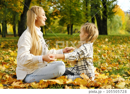 The family has fun in the park. Girl and mother sit on a blanket and rest The family has fun in the park. Girl and mother sit on a blanket and rest 105505728