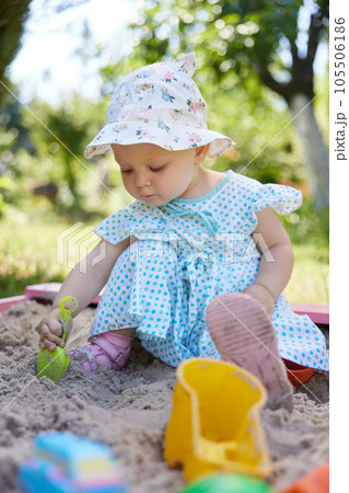 baby girl playing in sand on outdoor playground 105506186