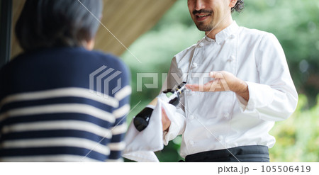 ワインの説明をするオーナーシェフ 105506419