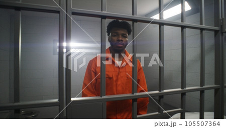 Man leans on prison cell bars and looks at camera 105507364