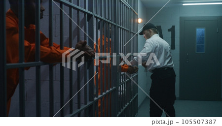 Prison employee brings new prisoner in jail cell 105507387