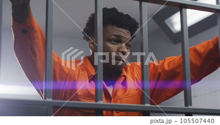 Man leans hands on jail cell bars and kneads neck 105507440