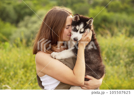 A beautiful young woman with her pet husky dog outdoors in the park 105507625