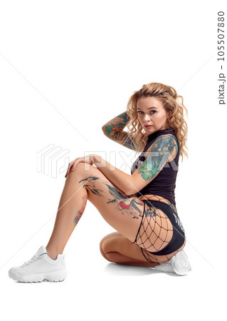 Sexy blond twerk woman with tattoed body and long curly hair is posing in studio. 105507880