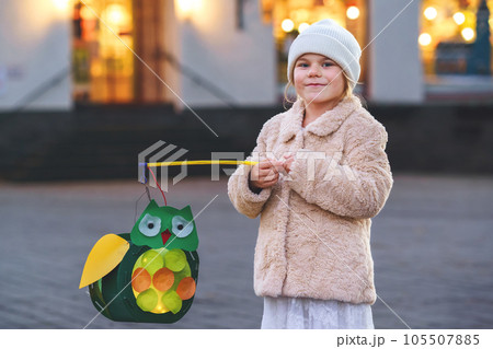 Little preschool kid girl holding selfmade traditional owl lanterns with candle for St. Martin procession. child happy about children and family parade in kindergarten. German tradition Martinsumzug 105507885