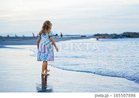 Happy Child, Little Preschool Girl in Dress Running And Jumping In The Waves During Summer Vacation On Exotic Tropical Beach by Sunset. Family Journey On Ocean Coast. Happy Child, Little Preschool Girl in Dress Running And Jumping In The Waves During Summer Vacation On Exotic Tropical Beach by Sunset. Family Journey On Ocean Coast. 105507898