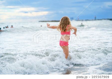 Happy Child, Little Preschool Girl in Swimmsuit Running And Jumping In The Waves During Summer Vacation On Exotic Tropical Beach. Family Journey On Ocean Coast. 105507909
