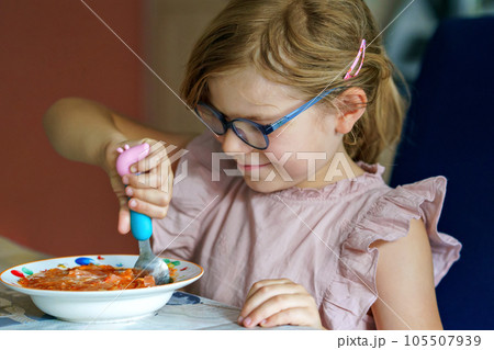 Little preschool girl eating from spoon vegetable potato soup. Healthy food for children. Happy kid at home or nursery. 105507939