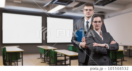Teachers stand against a blurred background of a classroom . 105508532