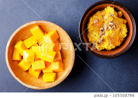 Sweet pumpkin porridge in clay bowl with raw pumpkin cubes 105508766