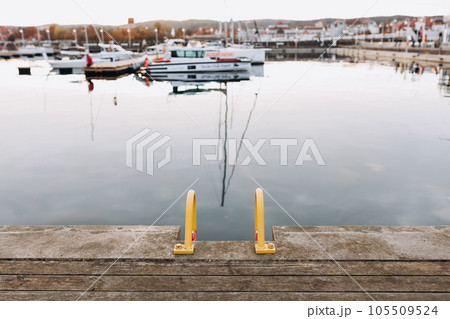 Old wooden pier with ladders. Many yachts and boats are moored at the pier. Boating and rest on the yacht. Vacation at sea. Selective focus. 105509524