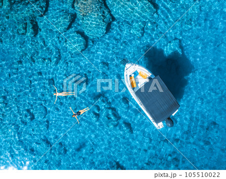 Aerial view of small motorboat and swimming people in the sea Aerial view of small motorboat and swimming people in the sea 105510022