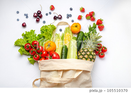 Grocery shopping. Different fresh fruit and vegetables in a textile shopper bag on white background, healthy food from supermarket or delivery concept. 105510370