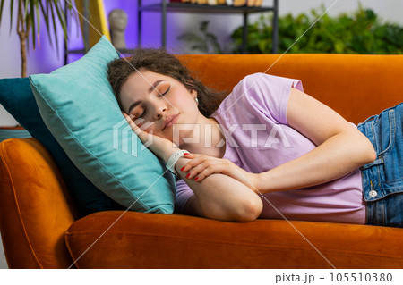 Tired young woman girl lying down in bed taking a rest at home, napping, falling asleep on couch 105510380