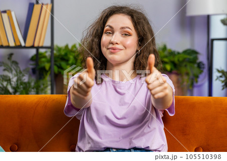 Happy young woman looking approvingly at camera showing thumbs up, like positive sign, good news 105510398