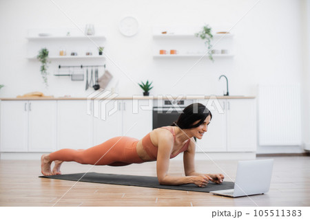Fitness woman doing plank and listening to music indoors Fitness woman doing plank and listening to music indoors 105511383