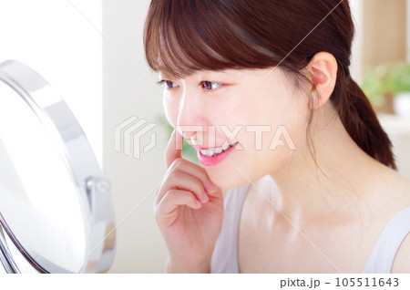 鏡を見ながら顔のスキンケアをする若い女性 鏡を見ながら顔のスキンケアをする若い女性 105511643