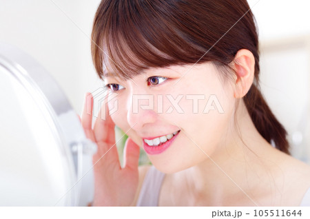 鏡を見ながら顔のスキンケアをする若い女性 105511644