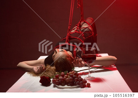 Alluring woman lying on the dinner table during BDSM game Alluring woman lying on the dinner table during BDSM game 105516397